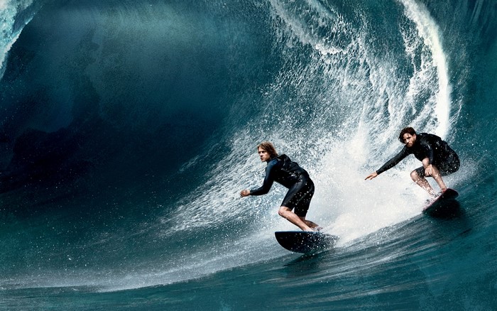 Two surfers riding a large wave