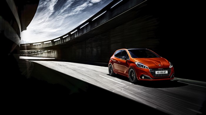 Orange Peugeot 208 driving on a road
