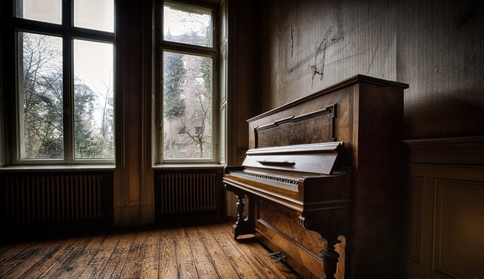 Old piano in a room with large windows