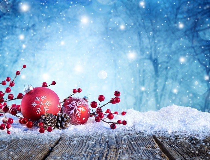Christmas ornaments and pine cones on snow-covered wood