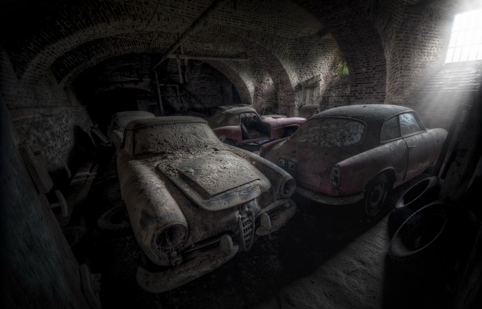 Abandoned vintage cars in a brick garage