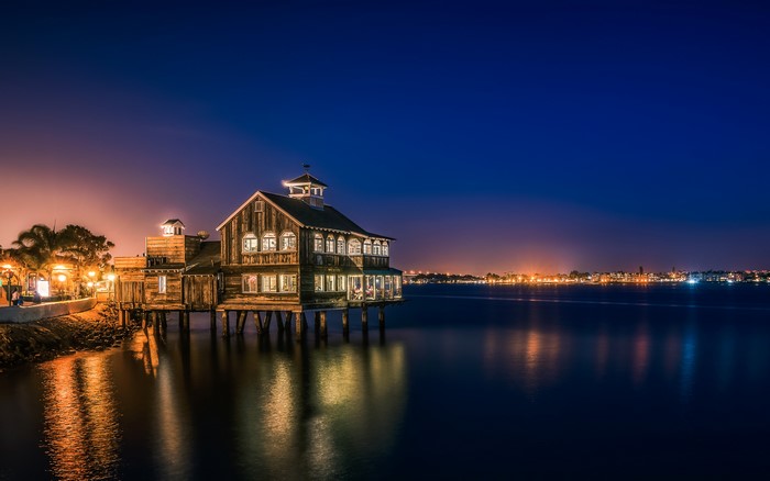 Wooden building on stilts over water at night in San Diego