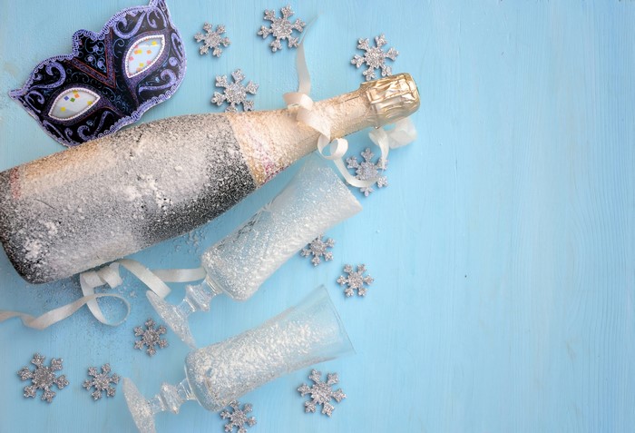 Champagne bottle and glasses with mask and snowflakes