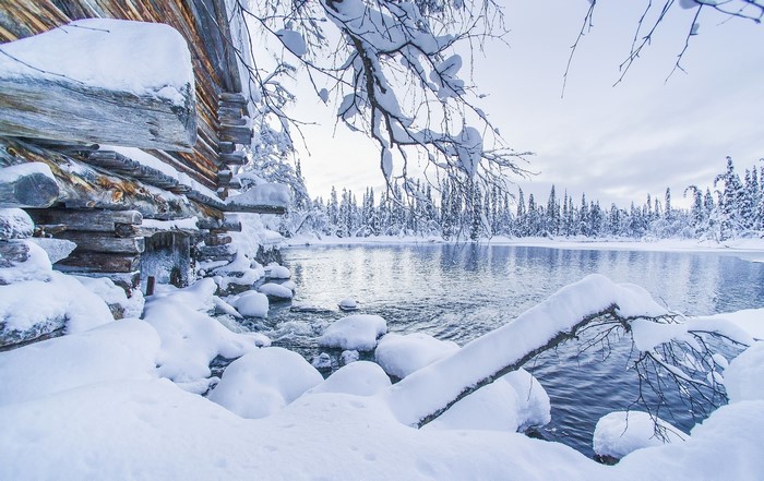 Winter scene with log cabin by a lake in Lapland