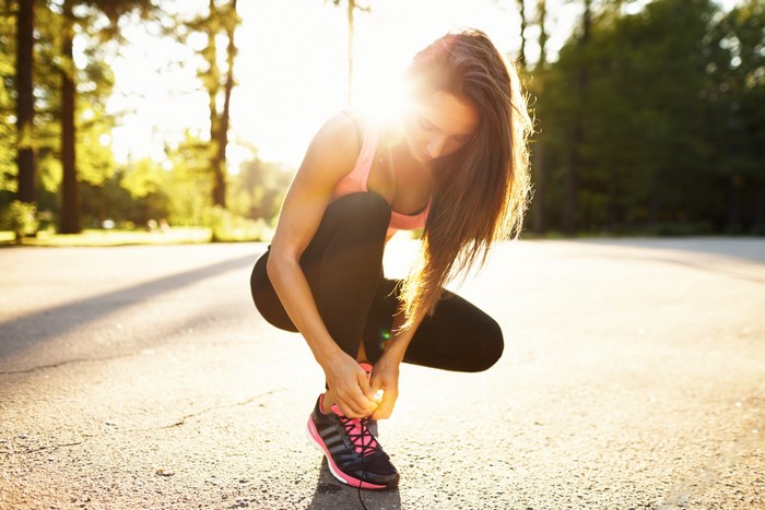 Woman tying her athletic shoe in a park
