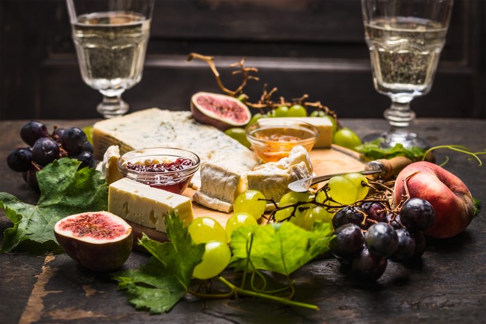 Cheese board with grapes, figs, jam, and wine