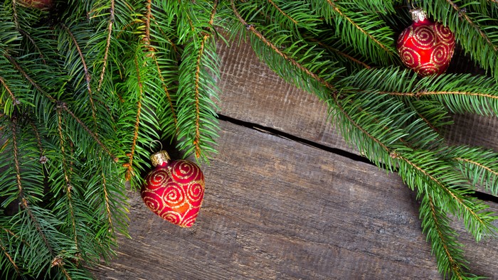 Christmas tree branches with ornaments on wooden background