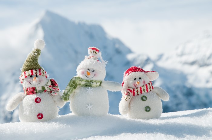 Three snowmen in a snowy mountain landscape
