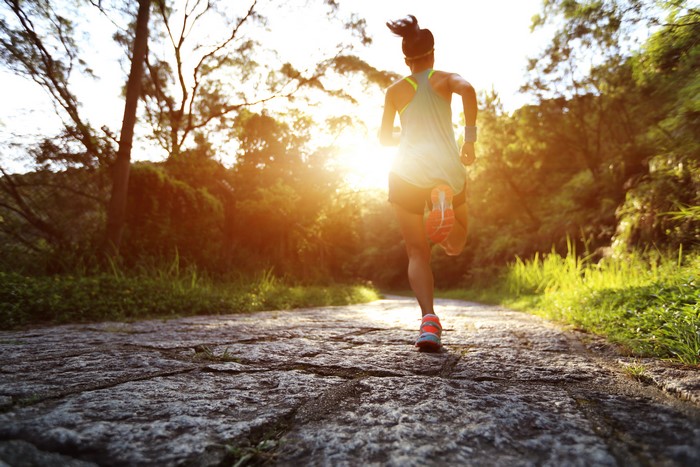 Woman running on a stone path during sunset