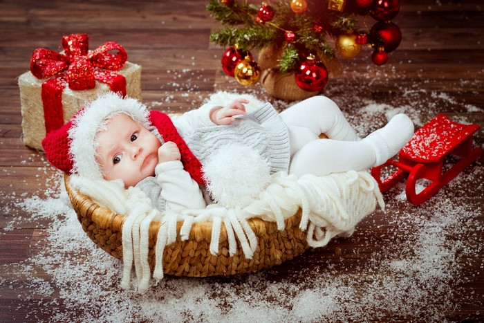 Baby in Santa hat with Christmas gifts and tree