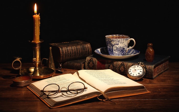Still life with candle, books, tea cup, and pocket watch