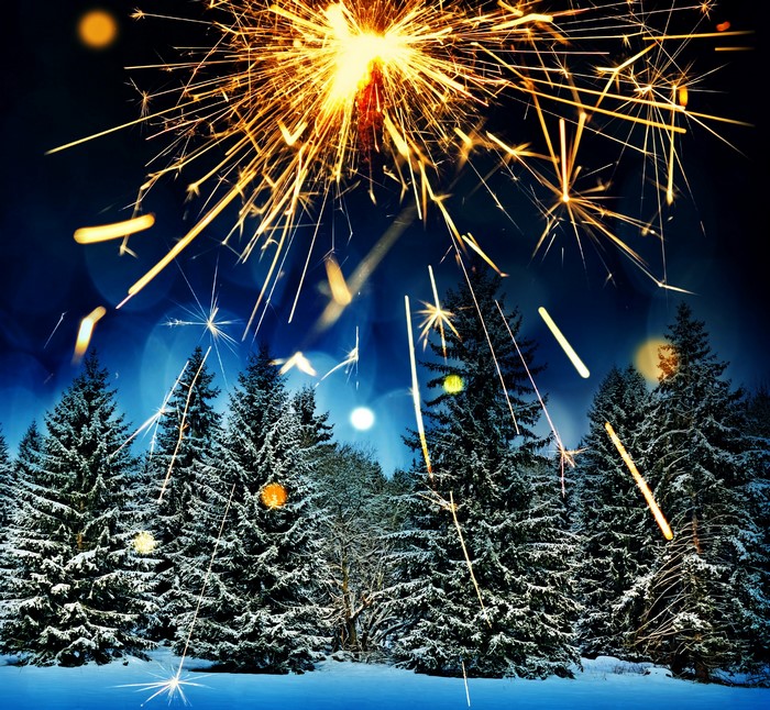 Sparklers over a snowy forest at night
