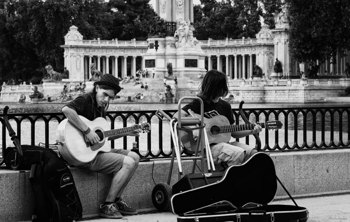 Two men playing guitars in front of a monument