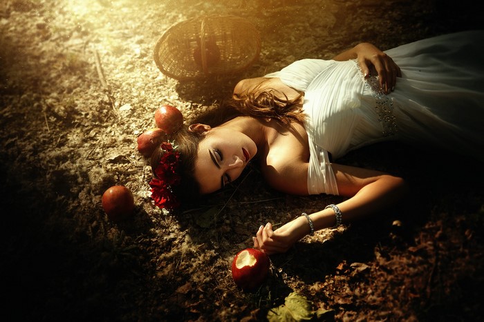 Woman in white dress lying with apples