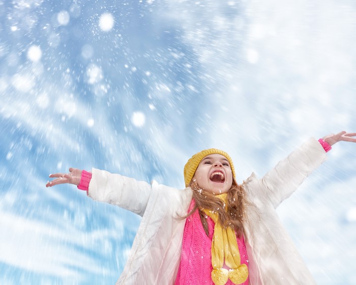 Girl in yellow hat and scarf enjoying snow