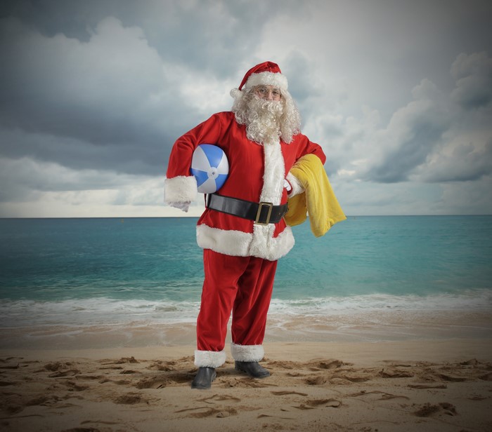Santa Claus on a beach with a beach ball and towel