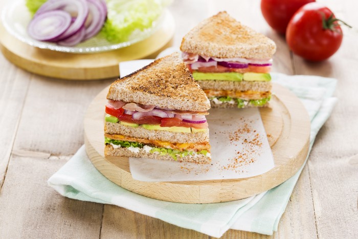 Two club sandwiches with avocado, tomato, and ham