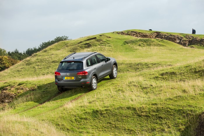Grey Volkswagen Touareg driving on grassy hills