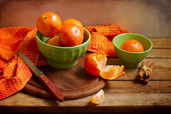 Mandarin oranges with cinnamon sticks and a knife