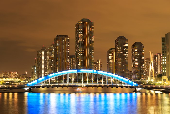 Tokyo skyscrapers and illuminated bridge over river at night
