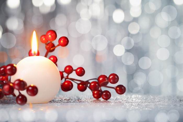 Christmas candle with red berries and bokeh
