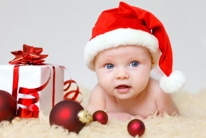 Baby in Santa hat with Christmas gifts and ornaments