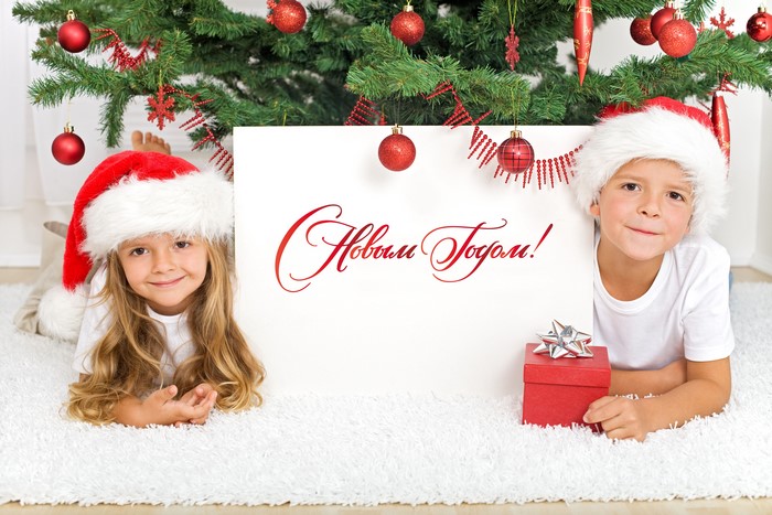 Children in Santa hats with Christmas tree and sign