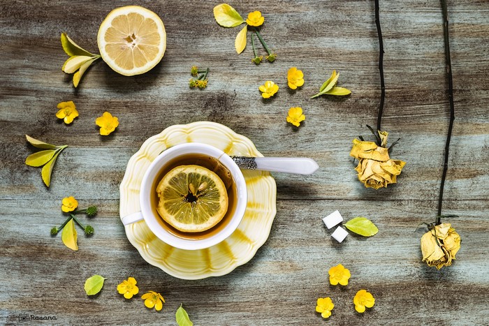 Tea with lemon and yellow flowers on a wooden table