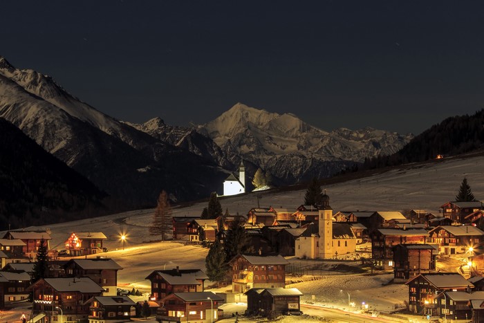 Snowy Swiss village at night with mountains