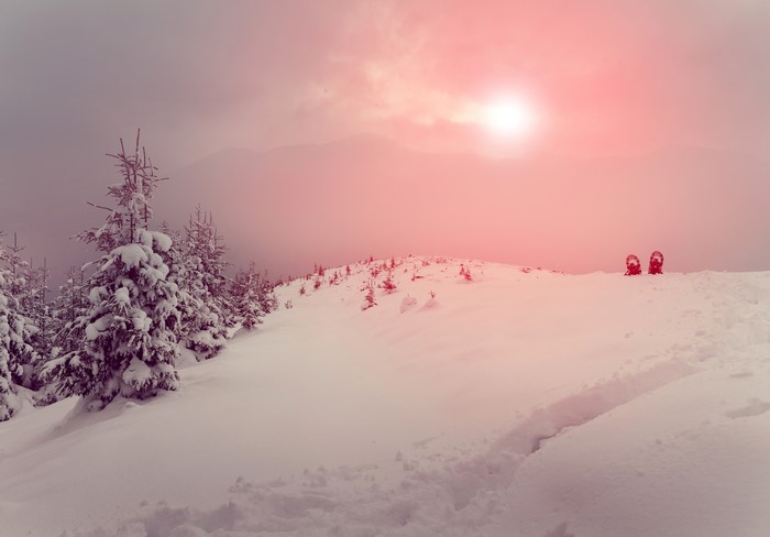 Snowy mountain ridge with sun and snowshoes