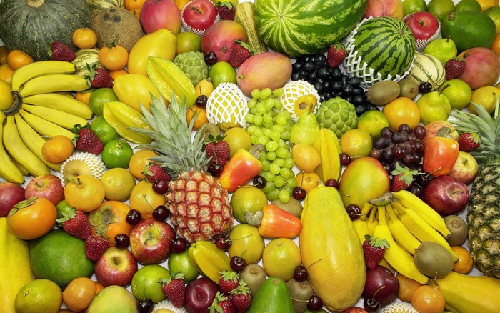 A vibrant assortment of fresh fruits including bananas, pineapples, grapes, and watermelons.