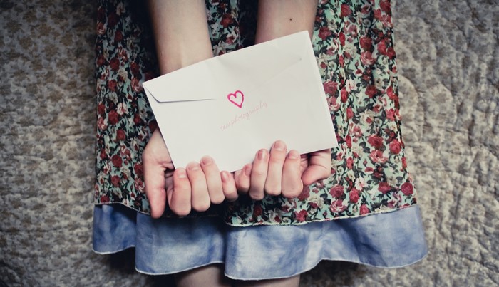 Hands holding an envelope with a heart and text
