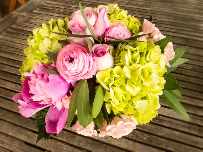 Pink and green floral arrangement on a wooden table
