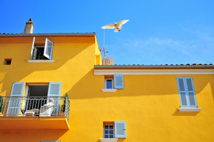Yellow House with Balcony and Flying Dove