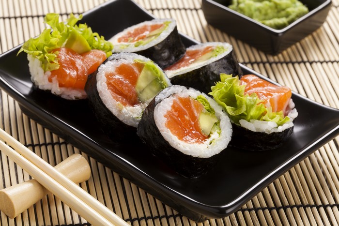 Salmon and avocado sushi rolls on a black plate