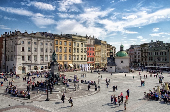 People in Krakow Town Square with colorful buildings
