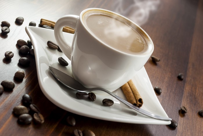 Coffee cup with beans and cinnamon sticks