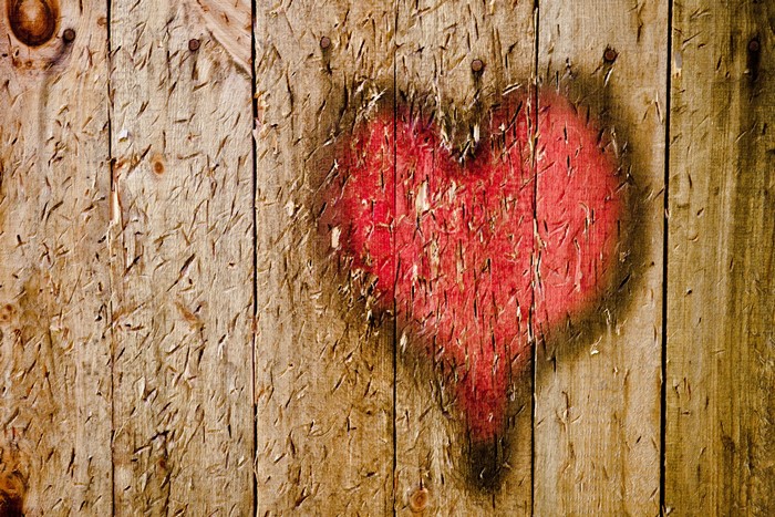 Red heart spray-painted on weathered wooden planks