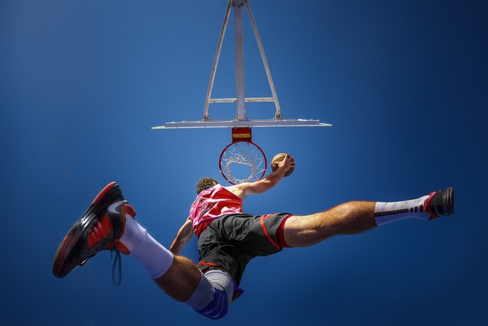 Man performing a slam dunk in a basketball game