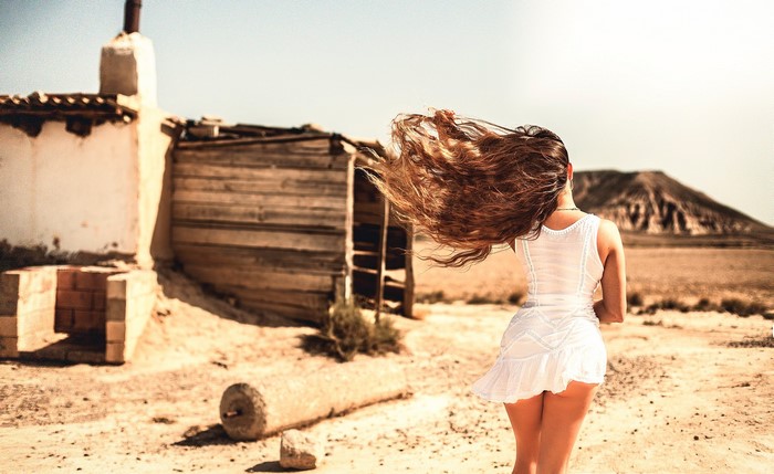 Woman with long brown hair in a white dress in the desert
