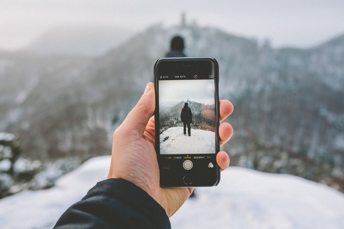 Person taking photo of person on snowy mountain with iPhone