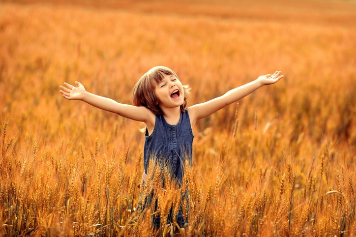 Young girl with arms outstretched in a wheat field