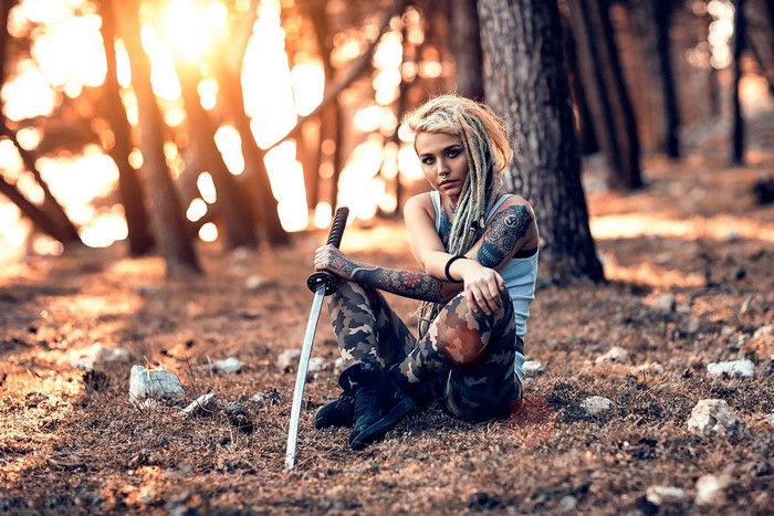 Woman with sword and tattoos in forest