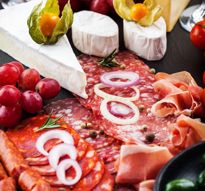 Charcuterie board with cheese, sausage, grapes, and onion