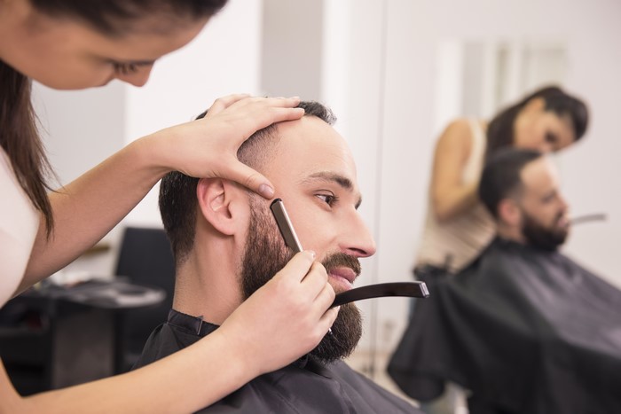 Barber shaving a man's beard with a straight razor