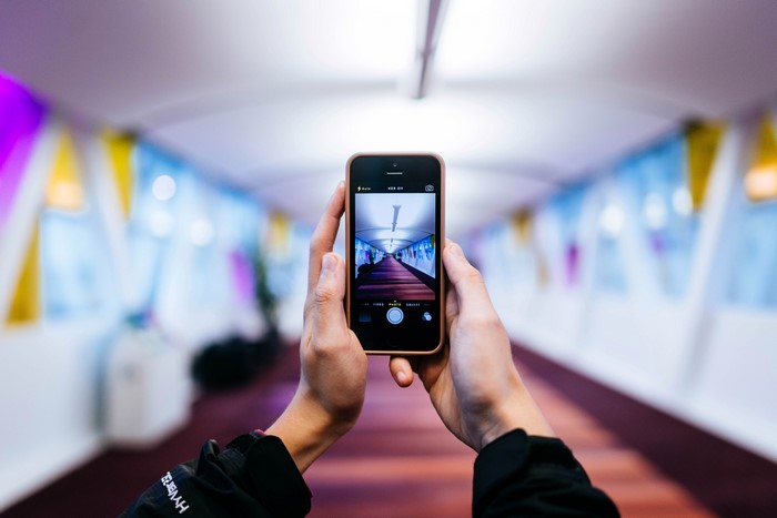 Hands holding iPhone taking a picture of a hallway