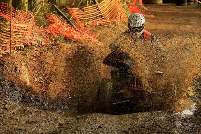 Person riding a quad bike through mud