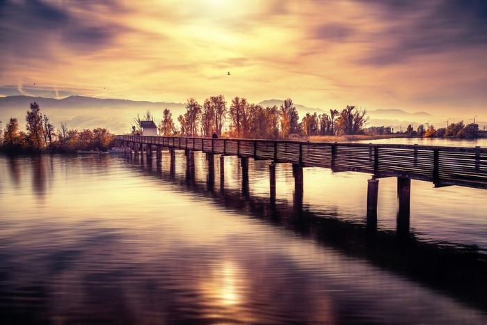 Wooden bridge over a river at sunset