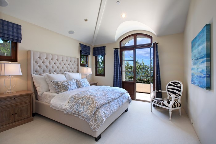 Bedroom with tufted bed and balcony doors