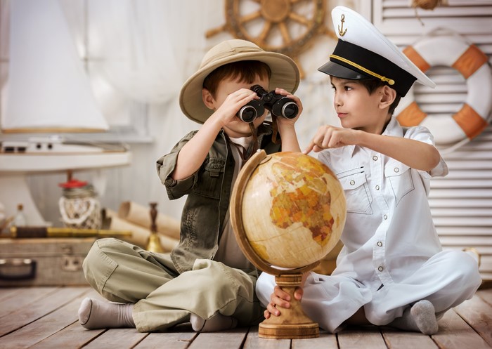 Two boys dressed as explorers and a captain with a globe